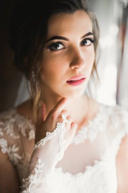 Cüppeli muhteşem gelin bir odada düğün töreni için poz veriyor ve hazırlanıyor.