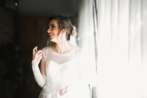 Preciosa novia en bata posando y preparándose para la ceremonia de boda cara en una habitación —  Fotos de Stock