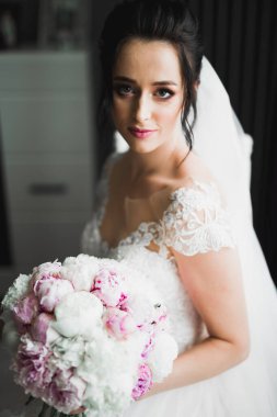 Gelin çiçekli büyük ve güzel bir düğün buketi tutuyor.