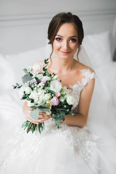 Роскошная свадебная невеста, девушка позирует и улыбается с букетом — стоковое фото