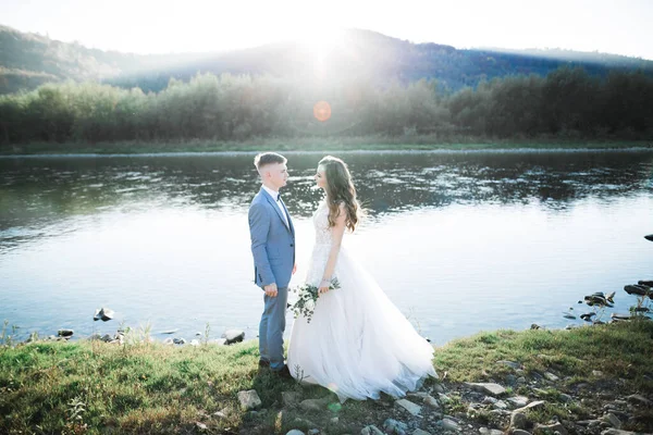Élégant élégant mariée blonde heureuse et marié magnifique sur le fond d'une belle rivière dans les montagnes — Photo