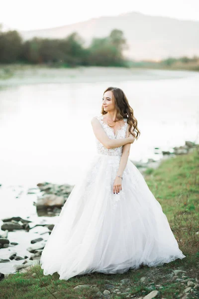 Ritratto di splendida sposa con lunghi capelli in piedi vicino al fiume — Foto Stock