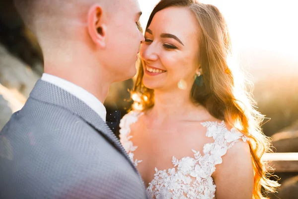 Hermosa novia con un ramo en el fondo de la montaña al atardecer — Foto de Stock