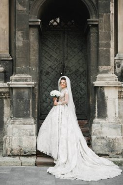 Gelin çiçekli büyük ve güzel bir düğün buketi tutuyor.