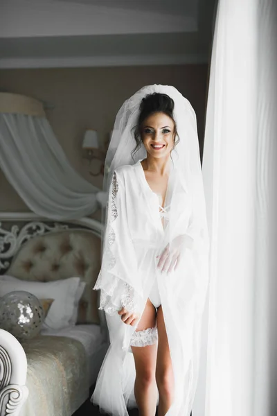 Bela noiva vestindo vestido de noiva de moda com penas com deleite de luxo maquiagem e penteado, estúdio sessão de fotos indoor — Fotografia de Stock