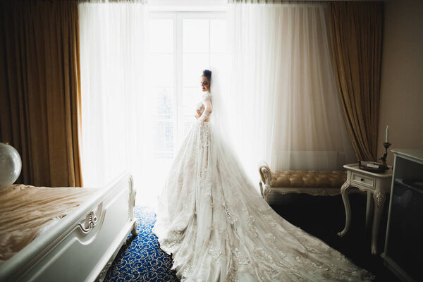 Красивая невеста в модном свадебном платье с перьями с роскошным макияжем и прической, студийная фотосессия