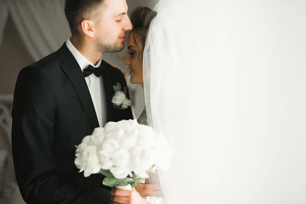 Schönes junges Hochzeitspaar posiert mit Blumenstrauß in den Händen — Stockfoto