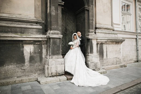 Casal feliz encantador do casamento, noiva com vestido branco longo posando na cidade bonita — Fotografia de Stock