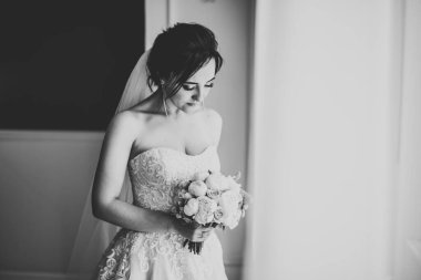 Lüks bir gelin, bir kız buketle poz veriyor ve gülümsüyor.