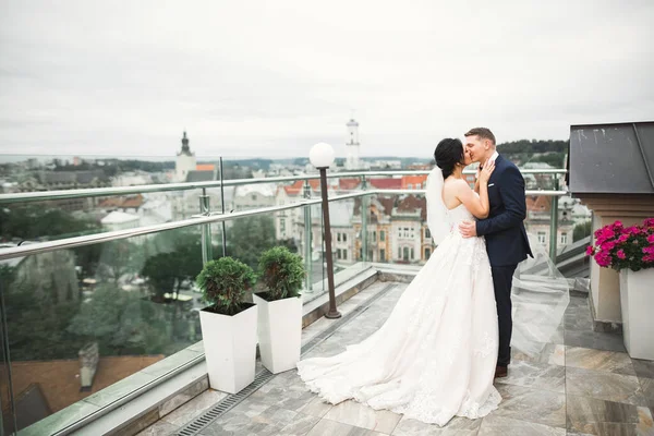 Gyönyörű menyasszony és vőlegény ölelkeznek és csókolóznak az esküvő napján a szabadban — Stock Fotó