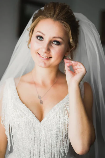 Hermosa novia con vestido de novia de moda con plumas con maquillaje de lujo deleite y peinado, estudio sesión de fotos interior — Foto de Stock