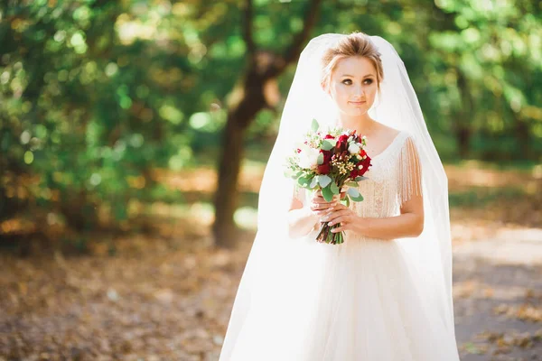 Роскошная свадебная невеста, девушка позирует и улыбается с букетом — стоковое фото