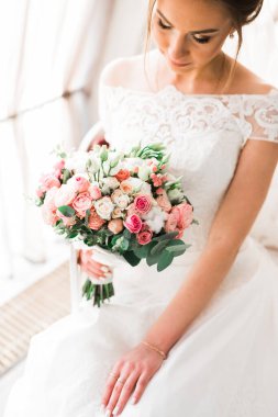 Gelin çiçekli büyük ve güzel bir düğün buketi tutuyor.