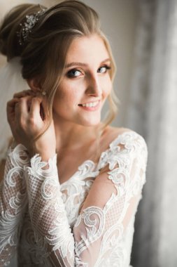 Beyaz elbiseli lüks gelin düğün törenine hazırlanırken poz veriyor.