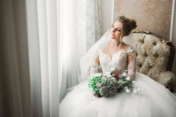 Noiva de luxo em vestido branco posando enquanto se prepara para a cerimônia de casamento — Fotografia de Stock