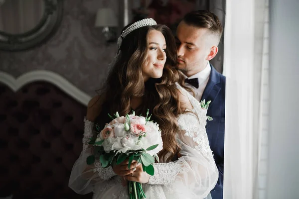 Schönes junges Hochzeitspaar posiert mit Blumenstrauß in den Händen — Stockfoto