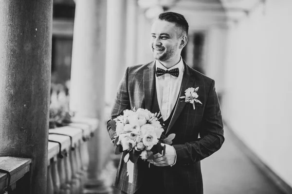 Šťastný pohledný usměvavý ženich pózující s boutonniere — Stock fotografie