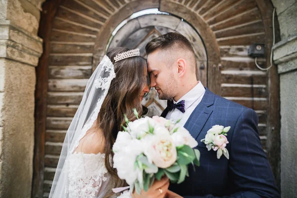 Hermosa joven pareja de boda posando con ramo de flores en las manos —  Fotos de Stock