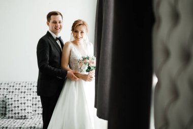 Güzel, genç bir çift ellerinde çiçeklerle poz veriyorlar.