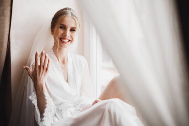 Cüppeli muhteşem gelin bir odada düğün töreni için poz veriyor ve hazırlanıyor.