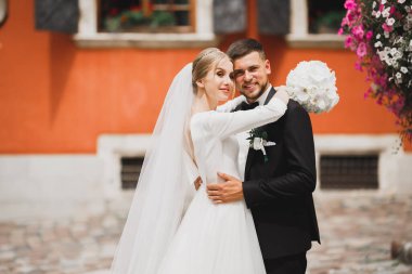 Güzel, genç bir çift ellerinde çiçeklerle poz veriyorlar.