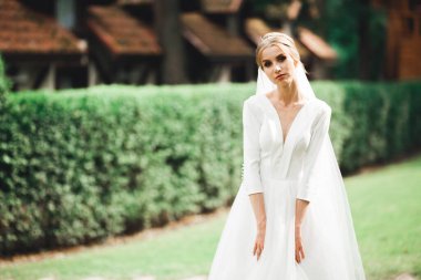 Parkta poz veren gelinlikli güzel, lüks bir gelin.