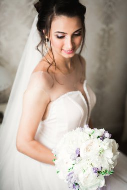 Cüppeli muhteşem gelin bir odada düğün töreni için poz veriyor ve hazırlanıyor.