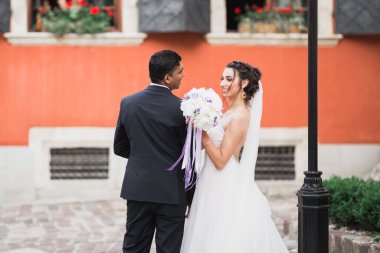 Doğadaki düğün çifti birbirine sarılıyor. Beyaz elbiseli güzel bir kız. Takım elbiseli adam