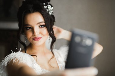 Güzel, gülümseyen bir gelin telefonda selfie çekiyor.