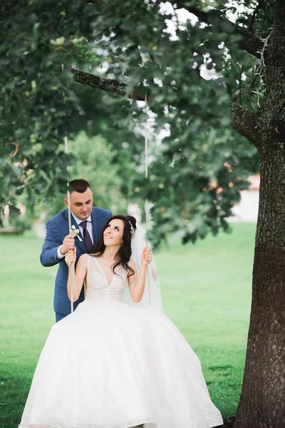 Hombre empujando a su esposa recién casada en un columpio — Foto de Stock