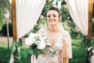 Gelin çiçekli büyük ve güzel bir düğün buketi tutuyor.