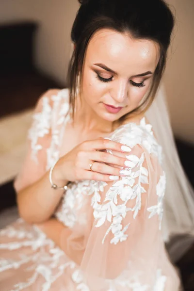 Hermosa novia con vestido de novia de moda con plumas con maquillaje de lujo deleite y peinado, estudio sesión de fotos interior — Foto de Stock