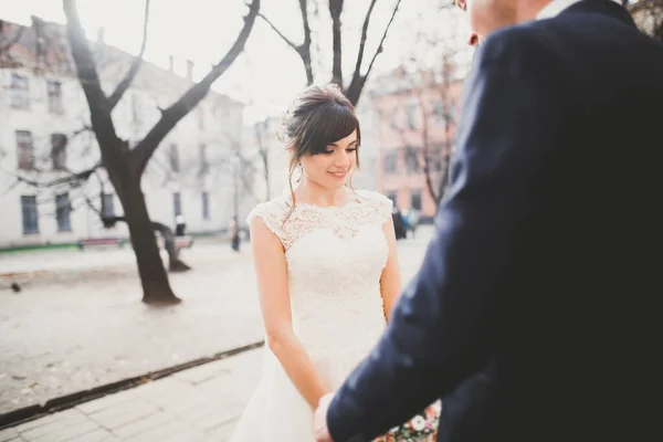 Casal elegante de recém-casados felizes andando no parque em seu dia de casamento com buquê — Fotografia de Stock