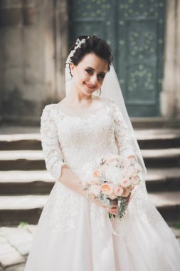 Çekici gelinin portresi, uzun saçlı, büyük buketli poz veren.