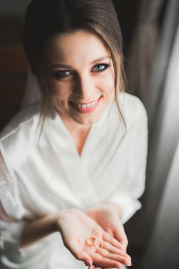 Beyaz elbiseli lüks gelin düğün törenine hazırlanırken poz veriyor.