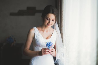 Cüppeli muhteşem gelin bir odada düğün töreni için poz veriyor ve hazırlanıyor.