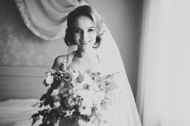 Cüppeli muhteşem gelin bir odada düğün töreni için poz veriyor ve hazırlanıyor.