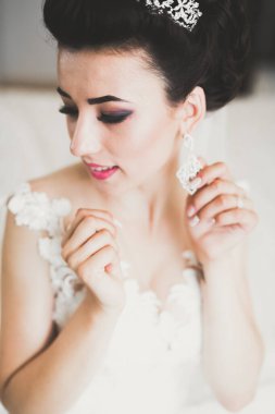 Cüppeli muhteşem gelin bir odada düğün töreni için poz veriyor ve hazırlanıyor.