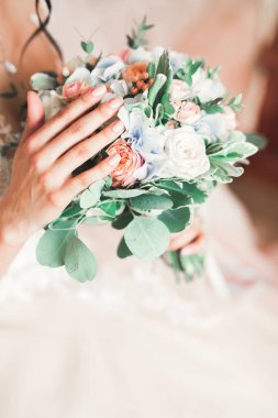 Gelin çiçekli büyük ve güzel bir düğün buketi tutuyor.