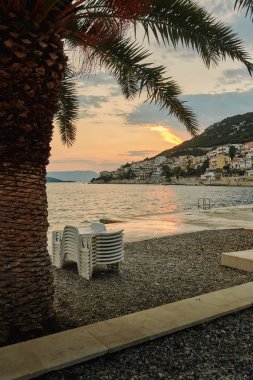 Boş plastik plaj şezlong sahilde günbatımı sırasında yığılmış.