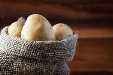 Çuval bezi ahşap arka plan üzerinde taze çiğ patates çuvalı. Kopya alanı