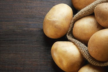 Çuval bezi ahşap arka plan üzerinde taze çiğ patates çuvalı. Kopya alanı ile üstten görünüm