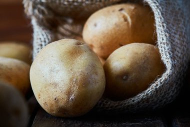 Ahşap arka plan üzerinde taze çiğ patates çuvalı çuval bezi