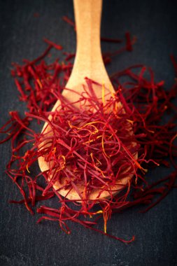 Tahta kaşık siyah arka plan üzerine safran baharat konular (lifler)