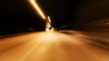 Bu video, gece vakti güzel bir caddenin durmaksızın çekilmiş bir görüntüsünü içeriyor. Hızlı hareket eden bir araçtan alınmış. Video, her iki tarafında renkli sokak ışıkları olan açık bir yol yakalıyor..