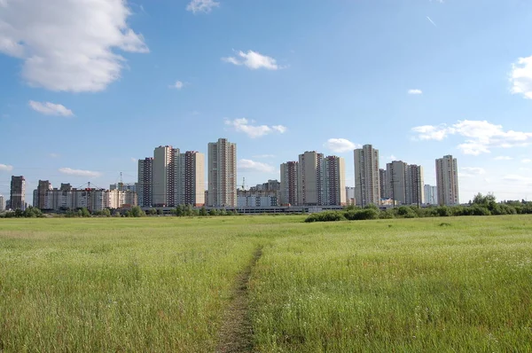 Высокие жилые здания на фоне большого поля и голубого неба — стоковое фото