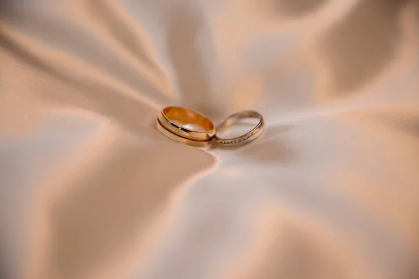 闪亮的布料上的结婚金戒指 — 图库照片