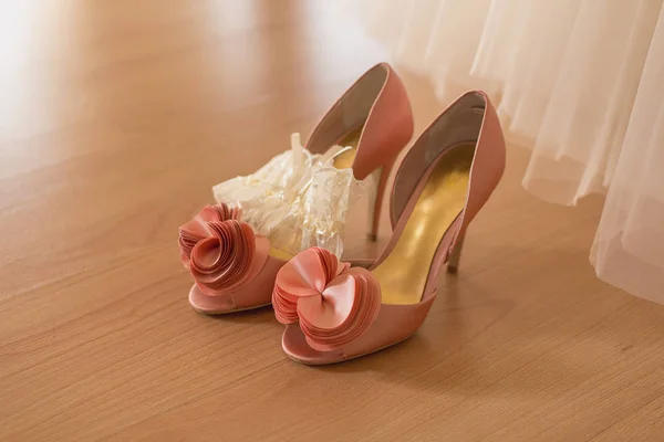 Van de bruid schoenen staan op de grond in de buurt van de trouwjurk — Stockfoto
