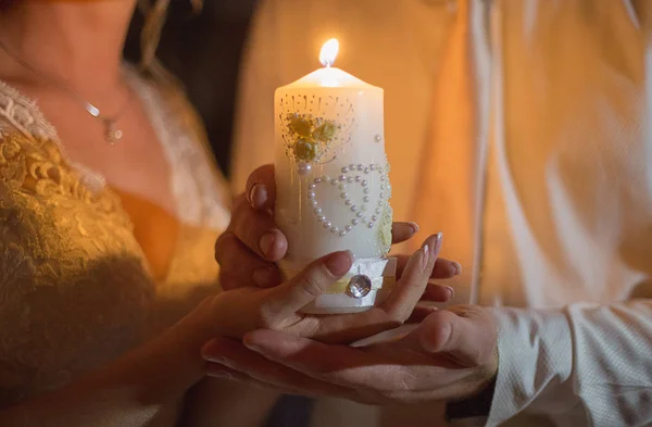 A noiva e o noivo mantêm uma grande vela em mãos — Fotografia de Stock