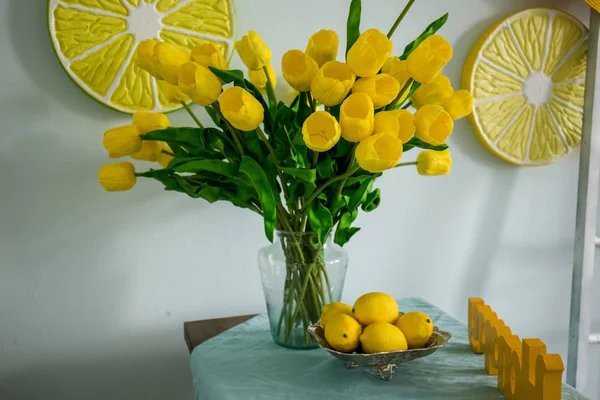 Yellow lemons and yellow tulips on the table — Stock Photo, Image